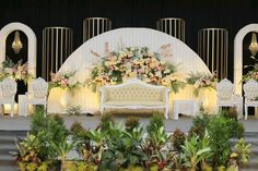 a stage set up for a wedding with flowers and greenery on the sidelines