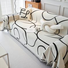 a couch covered in a black and white design with pillows on it's back