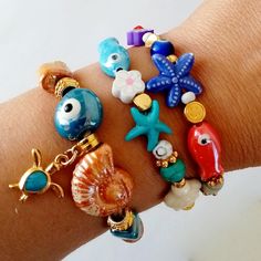 Beautiful handmade bracelets with Greek Porcelain beads, golden charms and very summery.  Here you have your looks ready for the holidays and for the whole summer.  I present you the trends in bracelets and very colorful jewelry for this summer. Ideal to wear alone or combine them with other summer jewelry.  In addition to being beautiful, they are great to carry good luck with you every day. Sold separately, choose the bracelet or bracelets you like best from the drop-down menu and show off a g Handmade Charm Bracelet For Beach, Bohemian Beaded Bracelets For Jewelry Making With Evil Eye, Bohemian Beaded Evil Eye Bracelets For Jewelry Making, Bohemian Evil Eye Beaded Bracelets For Jewelry Making, Bohemian Evil Eye Bracelets For Beach, Handmade Charm Bangle For Beach, Handmade Gold Evil Eye Bracelet For Beach, Handmade Bangle Charm Bracelet For Beach, Handmade Bohemian Evil Eye Bracelet Gift