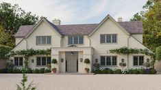 a large white house with lots of windows and plants on the front door is shown