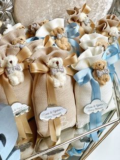 several teddy bears are wrapped in burlocks and tied with blue ribbon on a silver platter