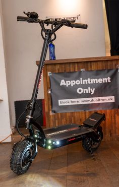 an electric scooter sits on the floor in front of a sign