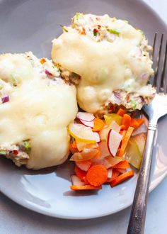 a white plate topped with meat covered in gravy and veggies next to a fork