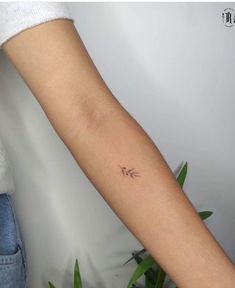 a woman's arm with a small arrow tattoo on the left side of her arm