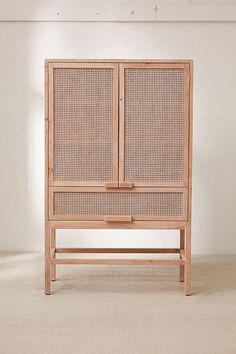 a wooden cabinet with wicker doors and drawers on the bottom, against a white wall