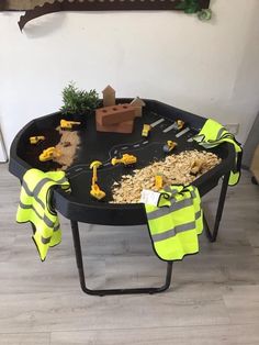 a table with construction themed items on it and yellow safety vests around the table