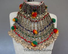 Long Kuchi nomad tribal choker necklace from Afghanistan. Colorful ornated with plastic and glass jewels, pompons and dangles held together by four double strands of glass seed beads. The jewels at the upper area are made of plastic and transparent screens put over a colored glittery foil, which is a very traditional way to create jewels in the Kuchi jewelry design. The metal color is brassy without silvertone parts. This choker is completely refurbished and has gotten a new black cotton lining Vintage Tassel Jewelry For Festival, Adjustable Tassel Jewelry For Festivals, Bohemian Necklaces With Dangling Beads For Celebration, Bohemian Beaded Necklaces For Celebration Festivals, Bohemian Beaded Necklace For Festivals And Celebrations, Multicolor Tassel Jewelry For Festival, Bohemian Multi-strand Choker For Festival, Bohemian Beaded Choker For Celebration, Bohemian Jewelry For Festival Celebrations