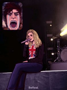 a woman sitting on top of a stage with a microphone in front of her face