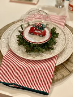 a plate topped with a red car under a glass dome on top of a table