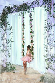 a woman in a pink dress is sitting on a swing with flowers and greenery