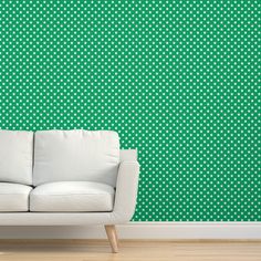 a white couch sitting in front of a green wall with polka dot pattern on it