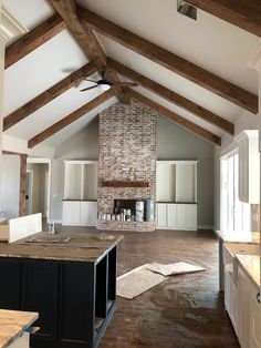 an empty kitchen and living room with exposed beams on the ceiling, wood flooring