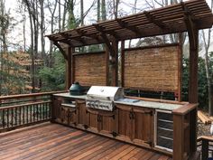 an outdoor kitchen on a deck in the woods