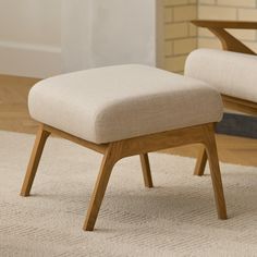 a chair and ottoman sitting on top of a carpeted floor next to a brick wall