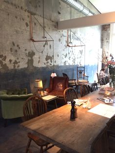 a room filled with wooden tables and chairs next to a wall covered in peeling paint