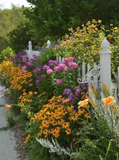 a white picket fence surrounded by colorful flowers