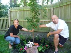 a man and woman kneeling down to plant a tree