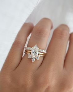 a woman's hand with two gold rings on it and a diamond ring in the middle