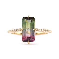 an emerald and pink tourmaline ring with diamonds on the band, set in yellow gold