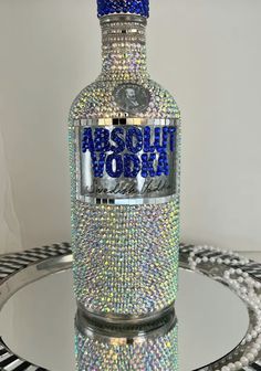 a bottle that is sitting on a table with some beads around it and the words absolut vodka in blue letters