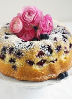 a blueberry bunt cake with powdered sugar and fresh flowers on the top