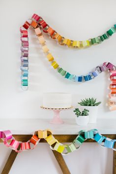 a cake sitting on top of a wooden table next to a rainbow streamer decoration