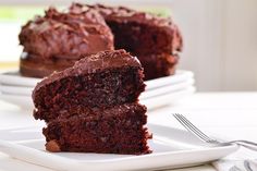 a piece of chocolate cake on a plate with a fork next to it and one slice missing