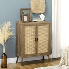 a wooden cabinet with wicker doors in a blue living room next to a window