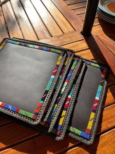 three notebooks sitting on top of a wooden table next to plates and utensils