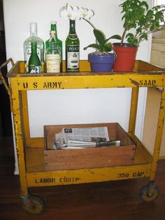 an old yellow utility cart with liquor bottles on it