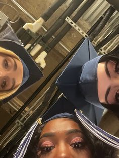 three women in graduation caps and gowns posing for the camera with their faces covered by fake hair