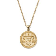 a gold necklace with an image of a scale and scales on it, hanging from a chain