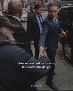 a man in a suit and tie is shaking hands with another man on the sidewalk