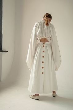 Crafted from a tough white cotton,  this mid-rise skirt is complemented by a wooden buttons back and two precise pleats. Pair with the collection's Vyshivanka cream blouse and play with proportions. Composition: 100% pure cotton Dry clean only  Handmade by women for women The model is 175 cm tall and wears S size White Skirt Summer, Walking Skirt, White Cotton Skirt, White Long Skirt, Cotton Maxi Skirts, Button Skirt, Full Length Skirts, Cream Blouse, Extra Long Sleeves