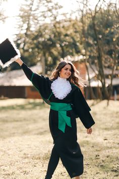 a woman in a black and green outfit is holding up a frisbee while walking through the grass