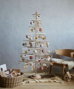 a white christmas tree sitting on top of a wooden floor next to a basket filled with ornaments