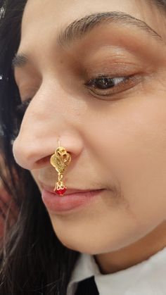 a close up of a person wearing a nose ring with a gold flower on it