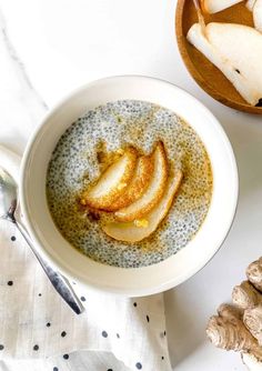 a bowl of oatmeal with sliced apples and ginger in it next to two spoons