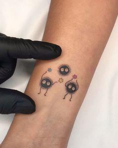 a person with a tattoo on their arm is holding onto the wrist that has two small cartoon characters attached to it