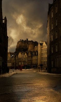 an empty city street with buildings on both sides and dark clouds in the sky above