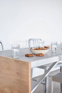 a bowl of food sitting on top of a metal table next to two empty glasses