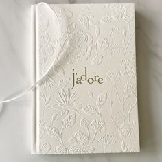 a white book with the word jadore on it sitting on a marble surface