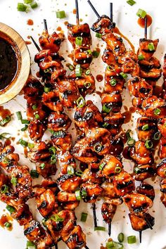 chicken skewers with sauce and green onions on a plate