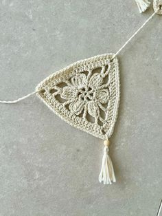 a white crocheted triangle with tassels hanging from it's sides