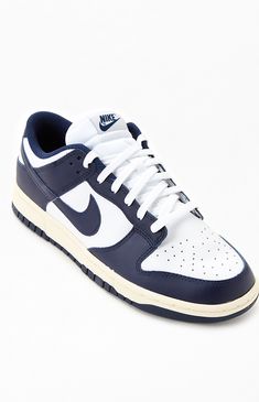 Online only! Nike's Vintage Navy Dunk Low Shoes bring a refreshing look to your sneaker collection. This ultra-popular low-profile shoe has a two-tone upper with a navy blue and white colorway and supplies leather overlays for a bold look. It's complete with a perforated toe and a padded collar.  PLEASE NOTE: This shoe is offered in men's sizes; please consult the Size Guide above - the conversion is a size and a half smaller for women. For example, a woman who is a size 7.5 should order a size Dunk Low Shoes, Storage Shoes, Shoes For School, Shoes Sneakers Jordans, Street Style Shoes, Low Shoes, Nike Vintage