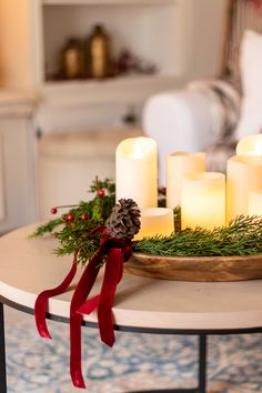 candles are arranged on a coffee table in front of a christmas wreath and pine cones