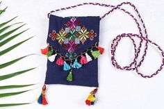 a blue bag with tassels and beads on it next to a palm leaf