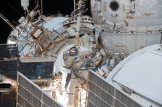 the space shuttle is being lifted from the ground by two men in spacesuits