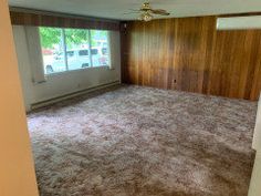 an empty room with wood paneling and carpet