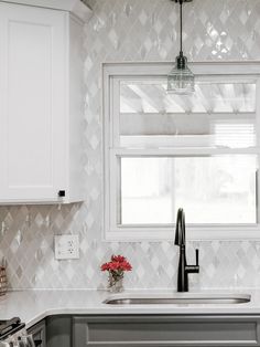 a kitchen with white cabinets and gray counter tops, an oven hood, and a window